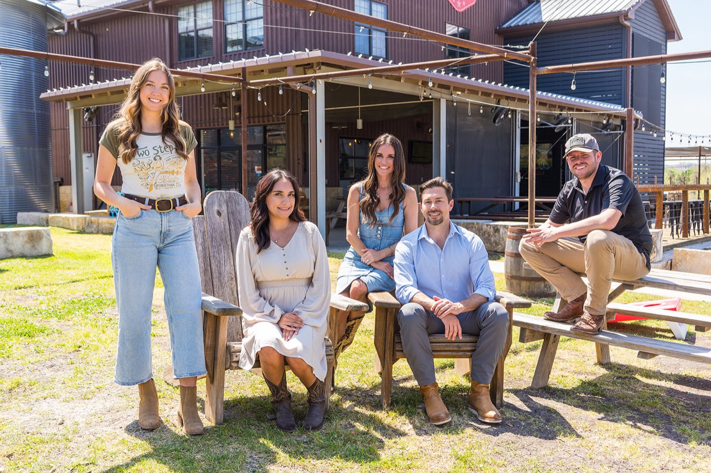 A group in branded caps gathered outside a ranch event barn