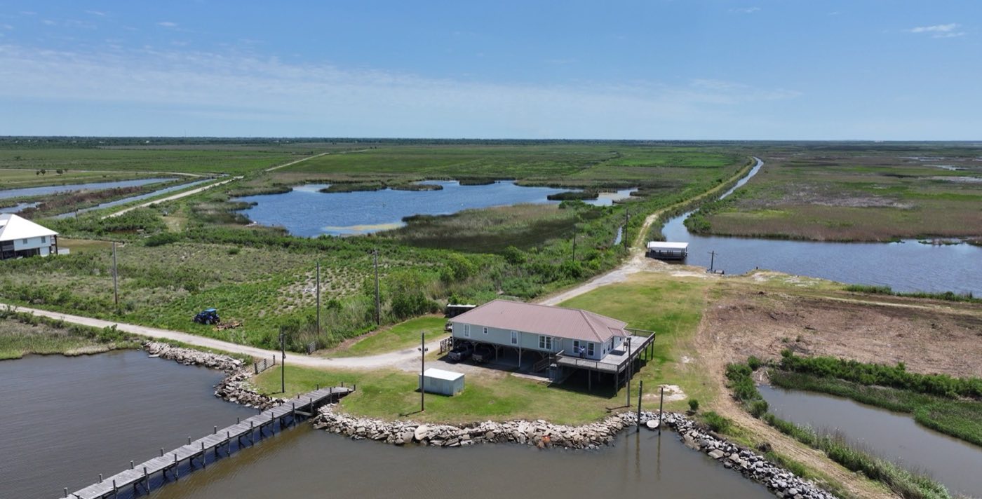 Aerial view of a coastal ranch property with a lodge beside open water