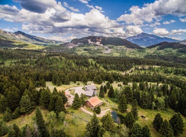 Aerial view of a mountain ranch surrounded by timbered ridges