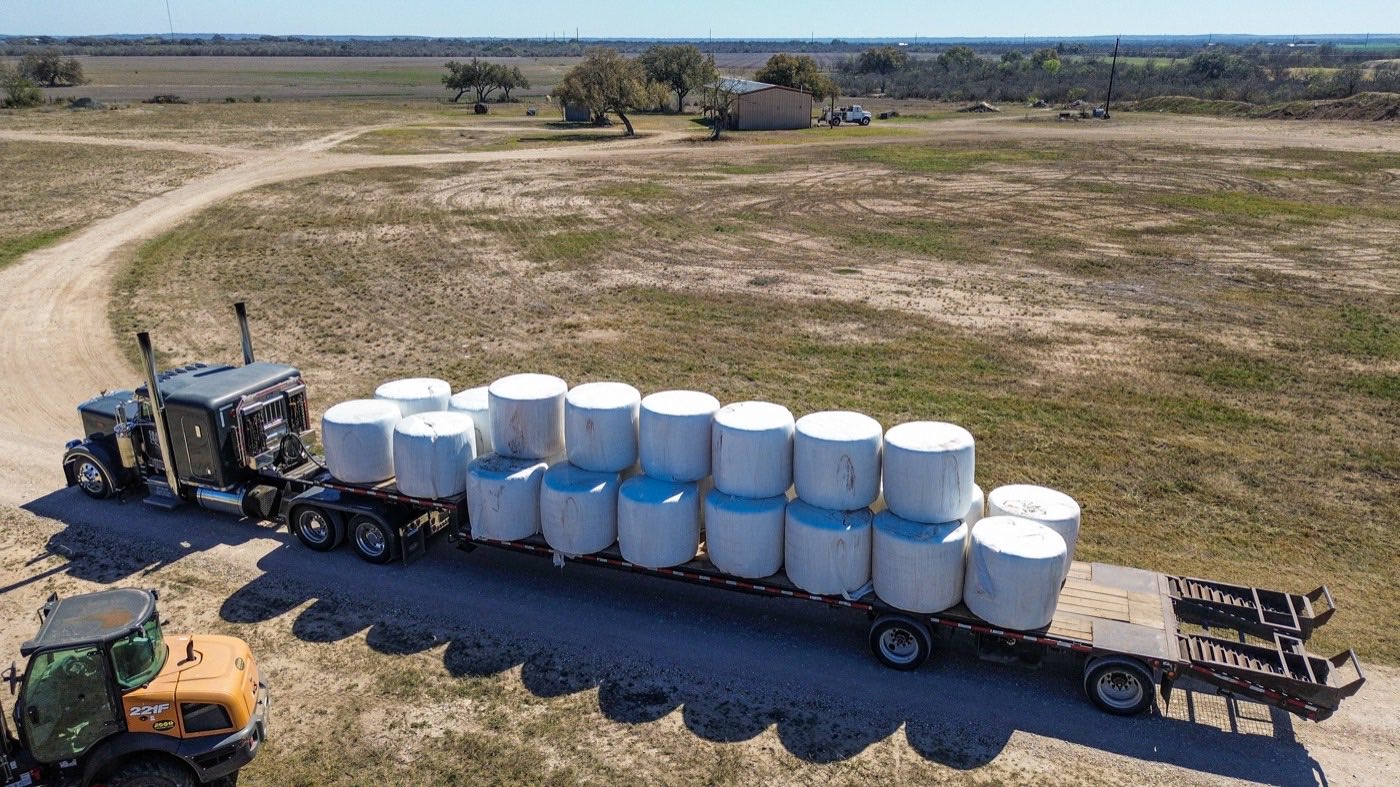An aerial view of a bulk feed truck loaded with tanks on a rural road