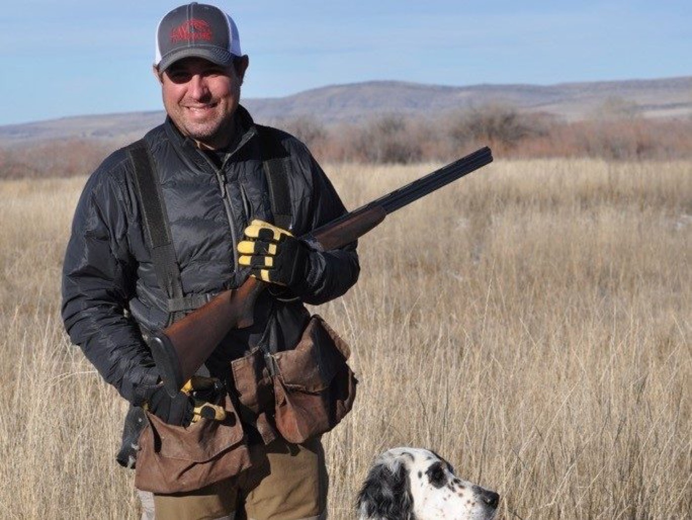 A ranch real estate agent in the field with his shotgun and bird dog